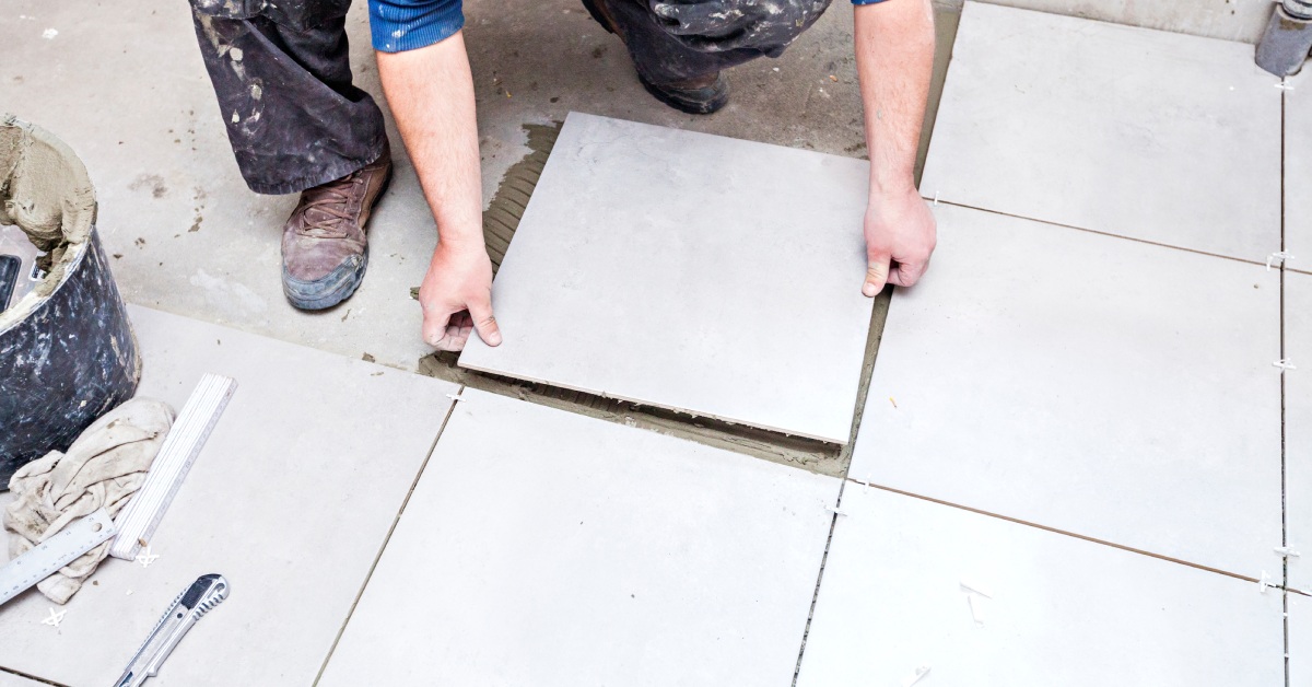 A professional contractor carefully installing tile flooring onto the ground as part of a larger bathroom remodeling project.