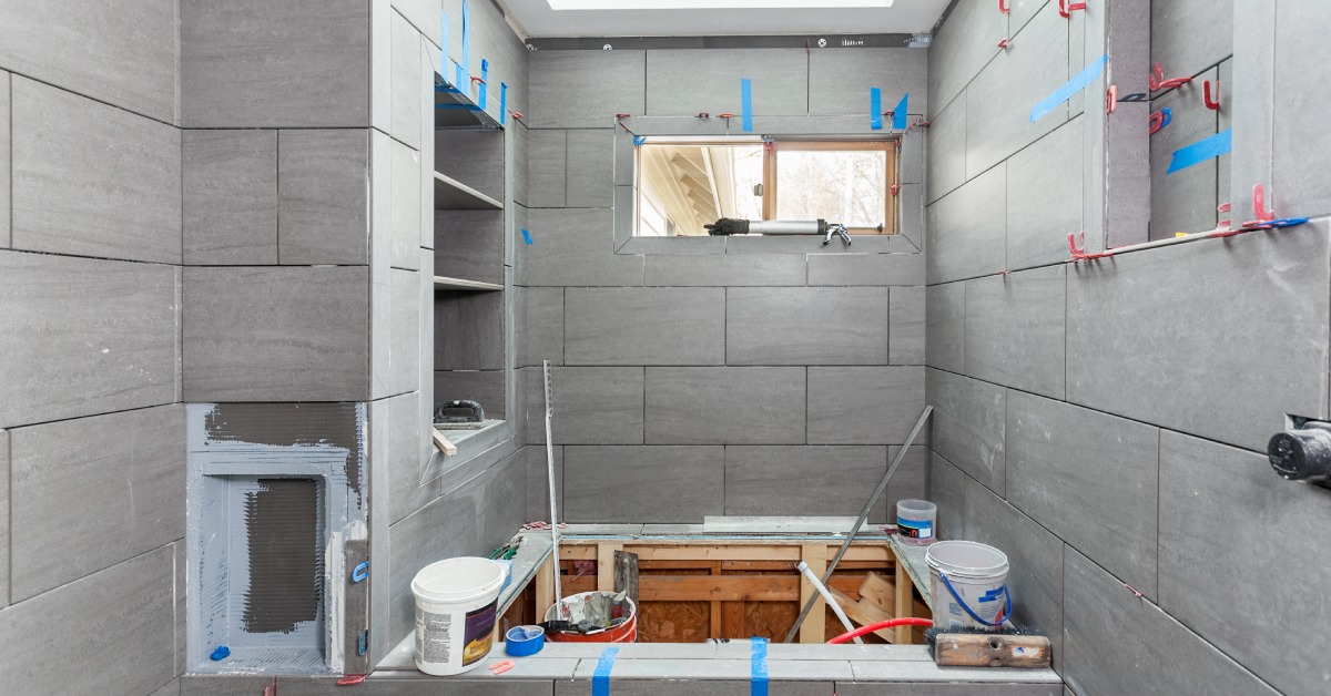 A bathroom in the middle of a remodeling project. The finished tile walls feature masking tape and exposed hook-ups.